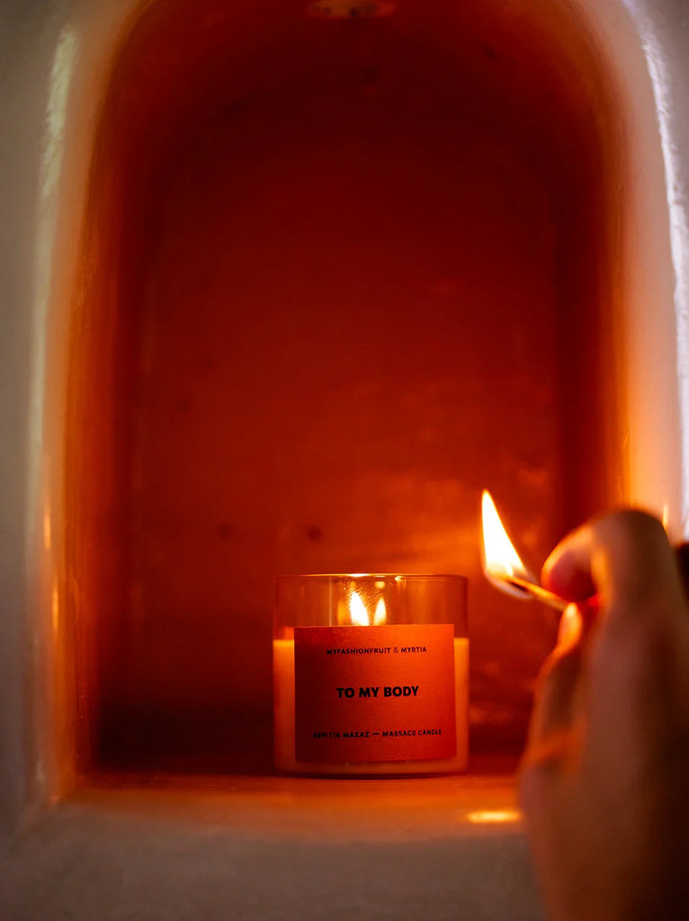 Massage Candle — Lit candle with orange label detail — MYFASHIONFRUIT